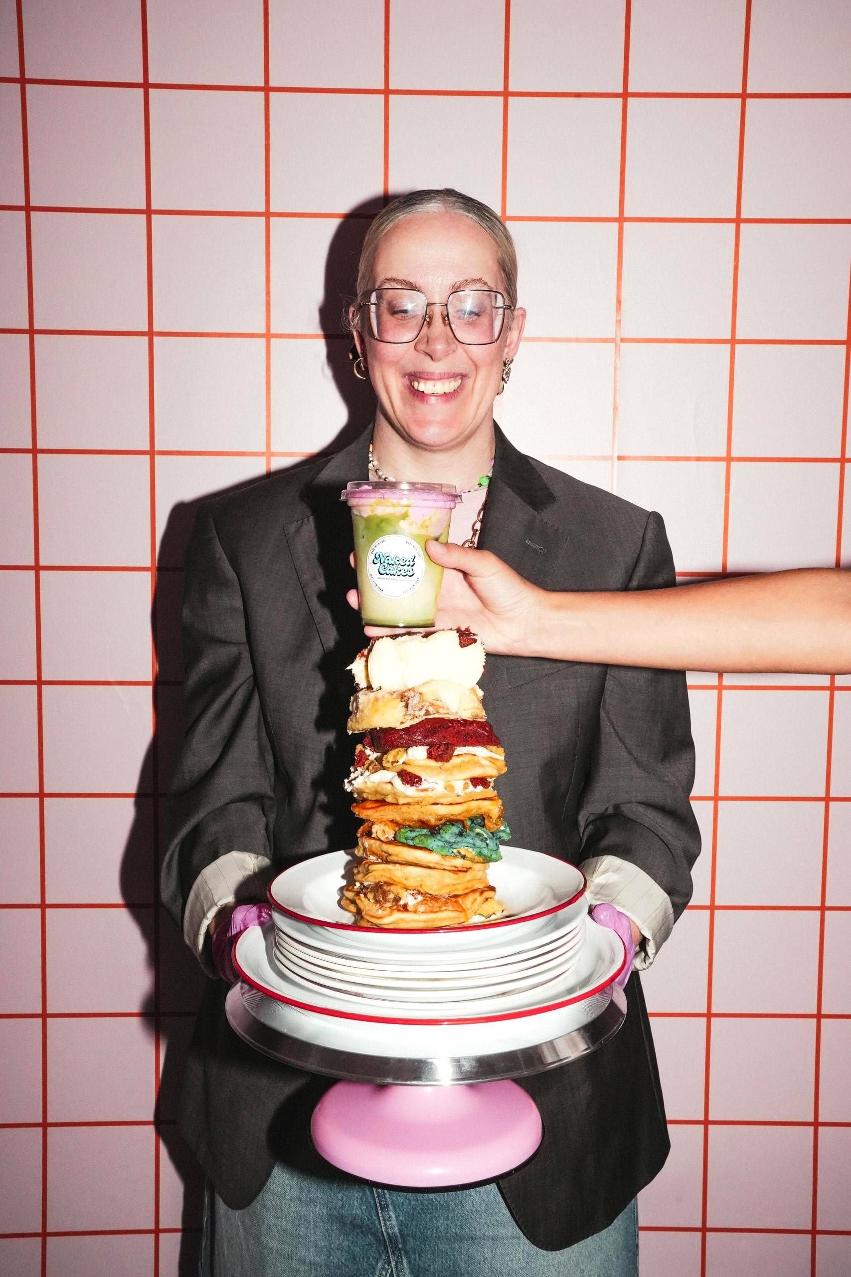 Jessie, founder of Naked Cakes, holding up a towering stack of cookies on a pink cake stand