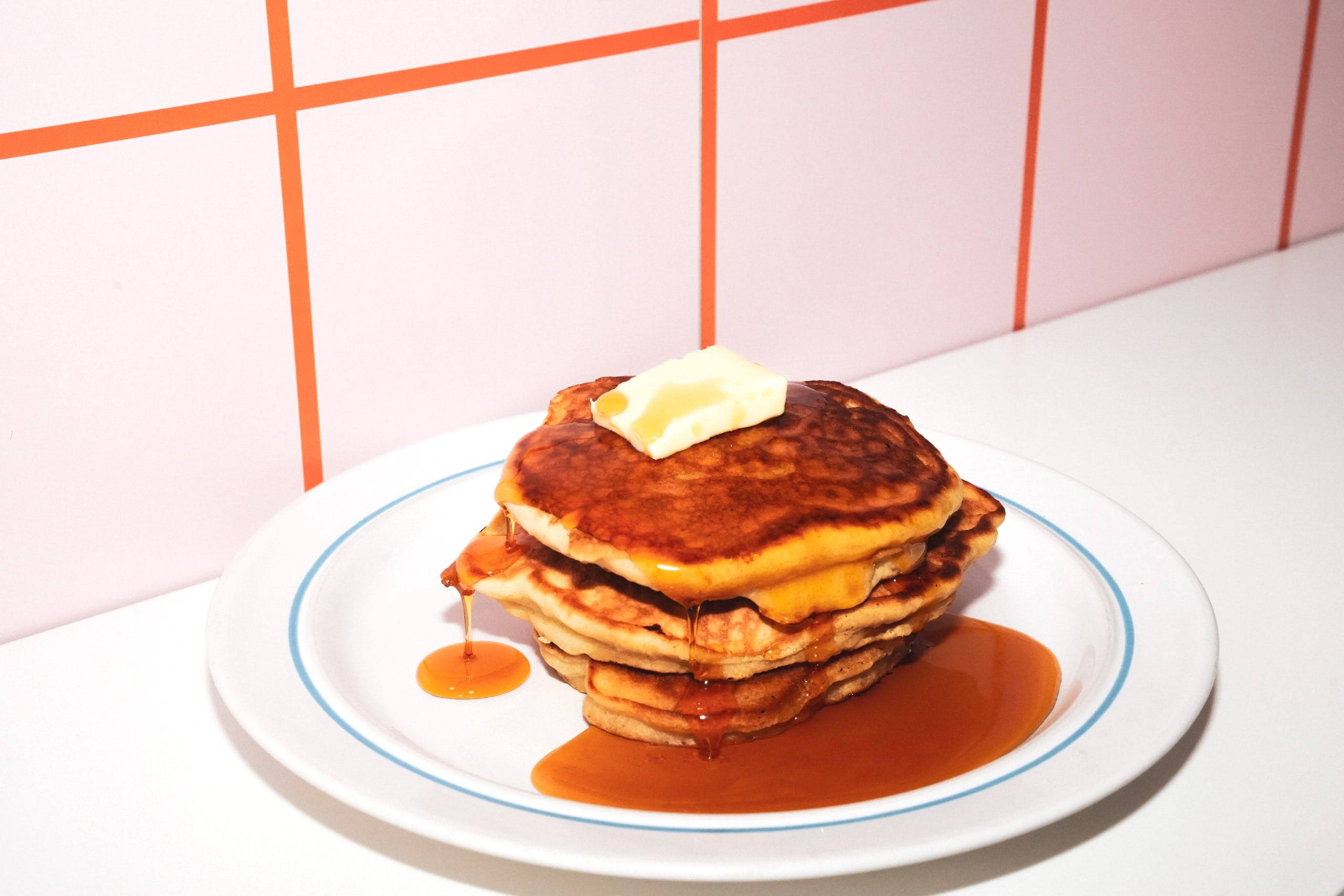 Stack of fluffy American pancakes with butter and syrup on a diner plate