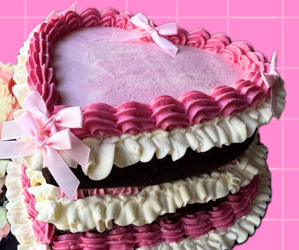 Pink vintage heart cake with ruffled cream piping and pink satin bows