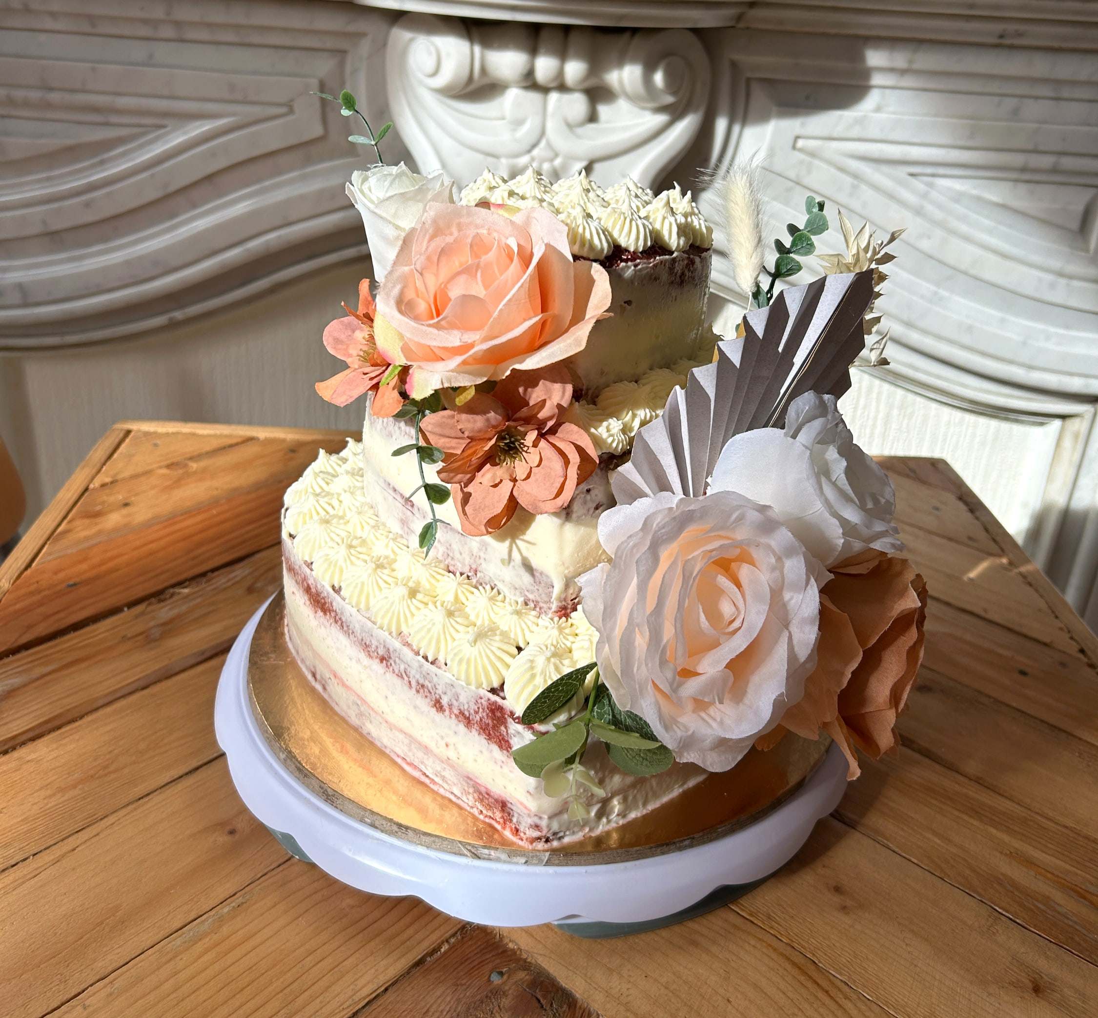 Two-layer red velvet wedding cake with cream cheese frosting, decorated with peach roses